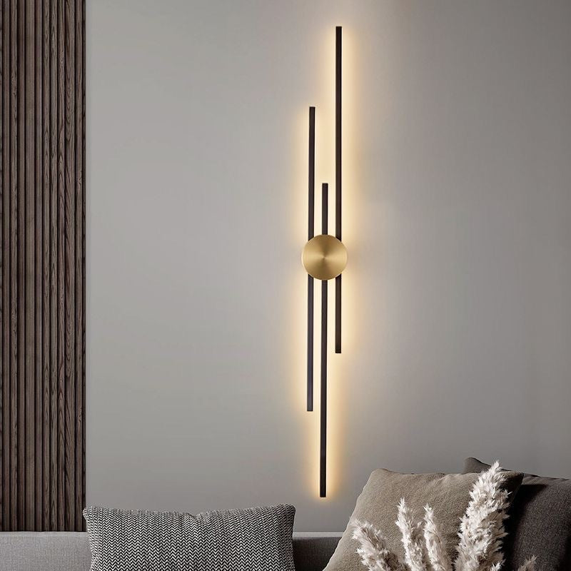 modern gold and black line wall lamp casting warm vertical glow above sofa in minimalist living room