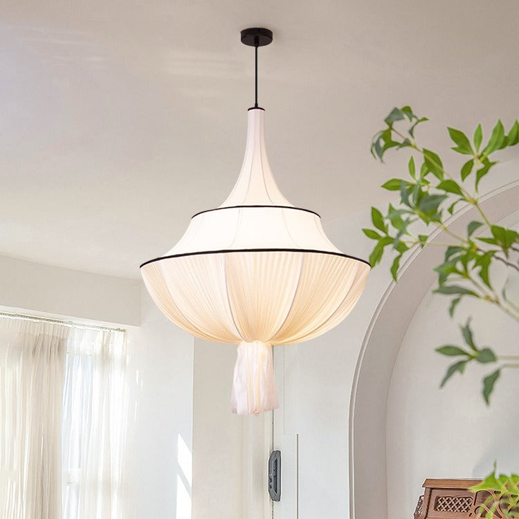 marianna art pendant hanging beside sheer linen curtain & fresh green foliage plant, warm minimalist cream interior with curved arch wall detail