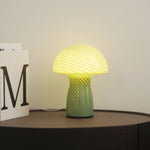 Green and yellow textured table lamp on a dark surface with a light background