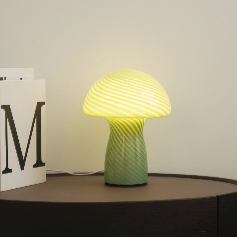 Green and yellow textured table lamp on a dark surface with a light background