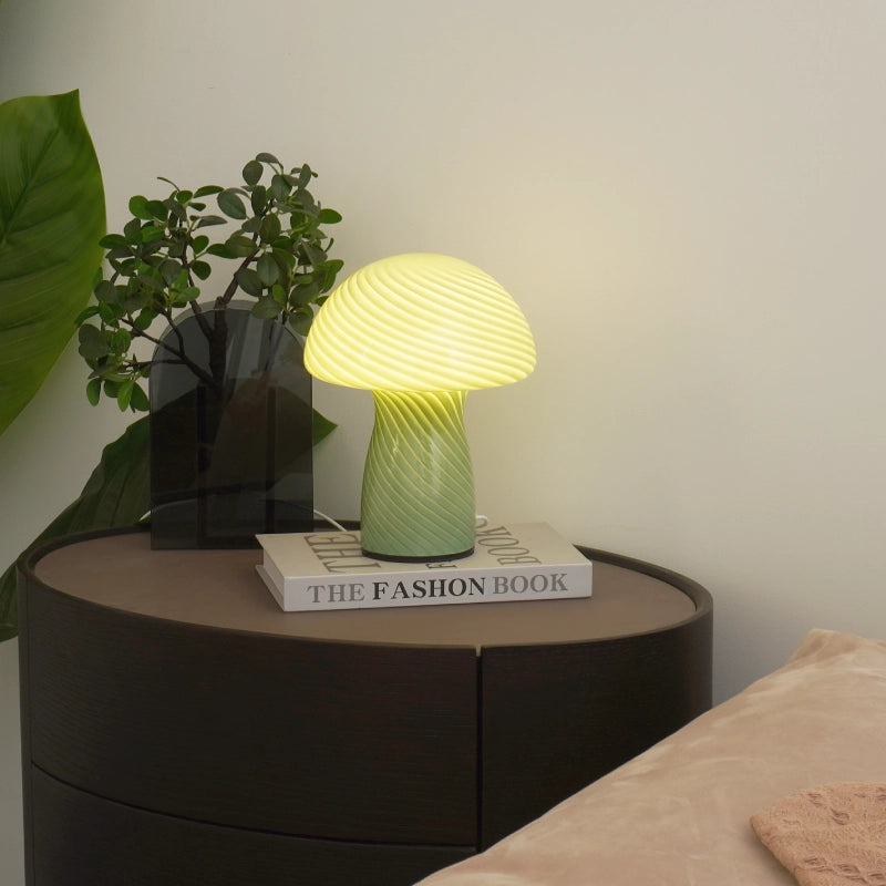 Mushroom-shaped lamp on a bedside table with a plant and book in the background