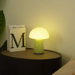 Lamp on a bedside table next to a book with a visible 'M' on a neutral background