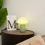 Table lamp on a bedside table with a book and plant in the background