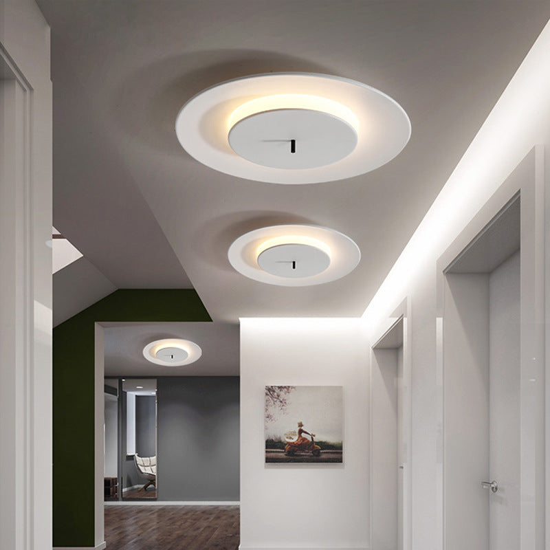 On the ceiling of the corridor, three white round ceiling lamps are arranged in a row, emitting warm light at the edges.