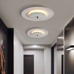 In the minimalist corridor, two white round LED ceiling lamps are arranged in an orderly manner on the ceiling.