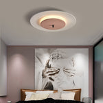 In the bedroom, on the ceiling, the pink and white round ceiling lamp made of metal is simple yet sophisticated.