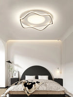 Sleek, curved ceiling fixture casts soft light, elevating the modern bedroom’s aesthetic.