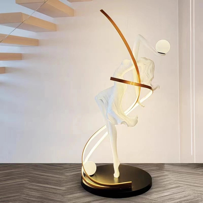 A graceful white female sculpture intertwined with golden curved LED arcs forms this artistic floor lamp, featuring spherical light accents on a sleek black base.