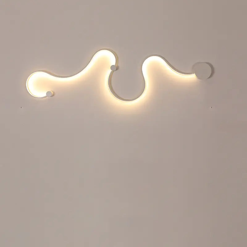 Overhead view of white silicone lamp’s snake-like curves against a monochromatic studio wall.