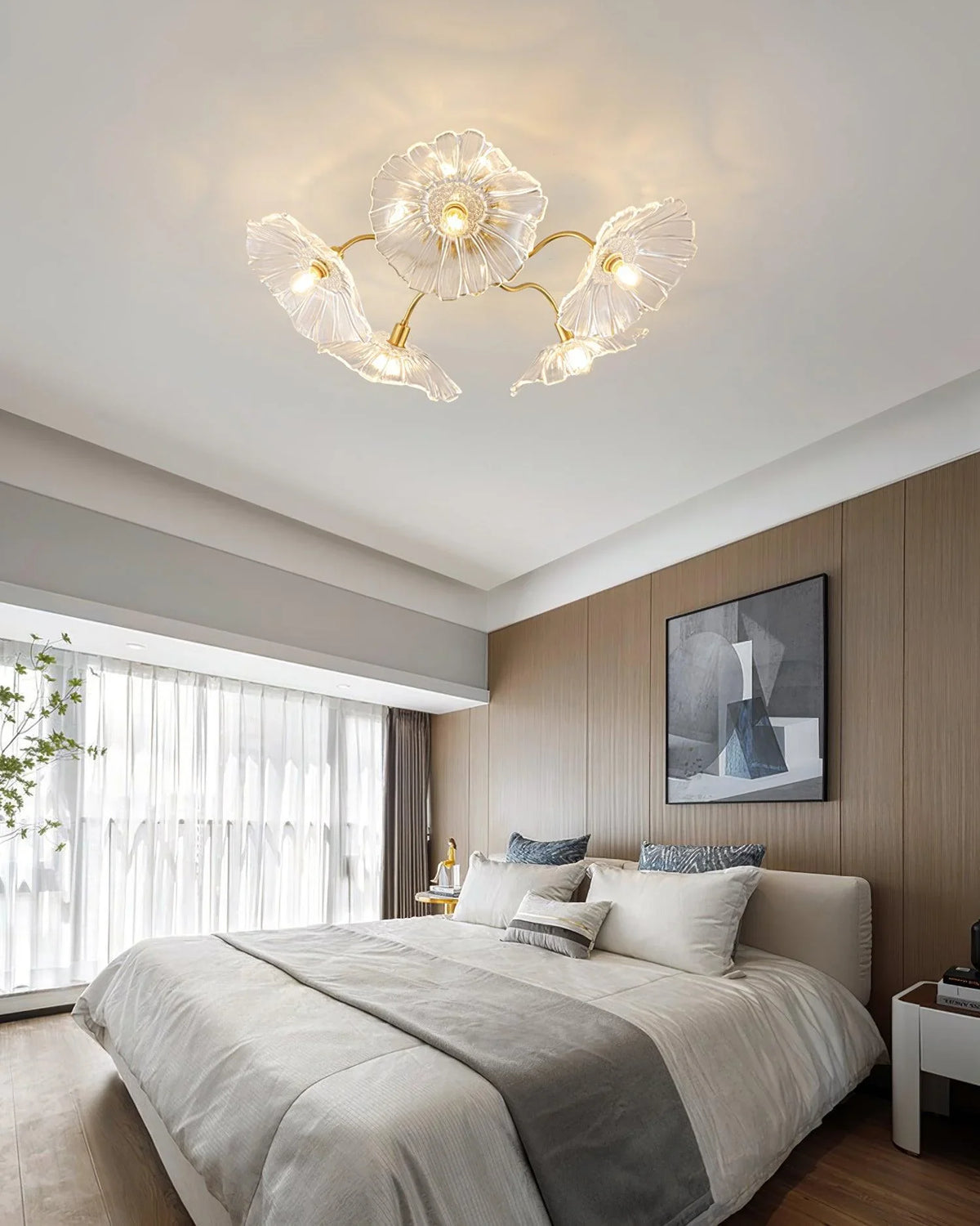 A ceiling lamp made of five clear glass petals emits a faint light in a modern bedroom