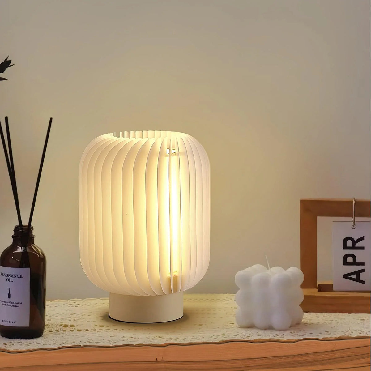 Soft ribbed table lamp casts warm light, enhancing bedside coziness with acrylic and fabric.