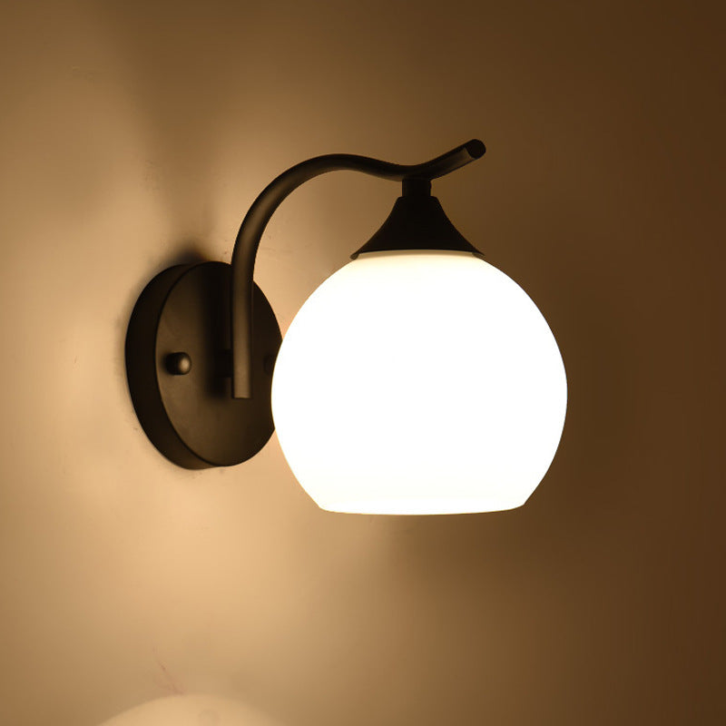 Warm glow curved arm globe wall sconce with frosted glass shade, creating a cozy ambient light effect