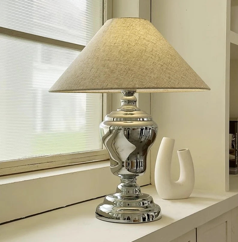 Nordic Simple Table Lamp with silver vase linen design rests on windowsill with soft natural light filtering through blinds