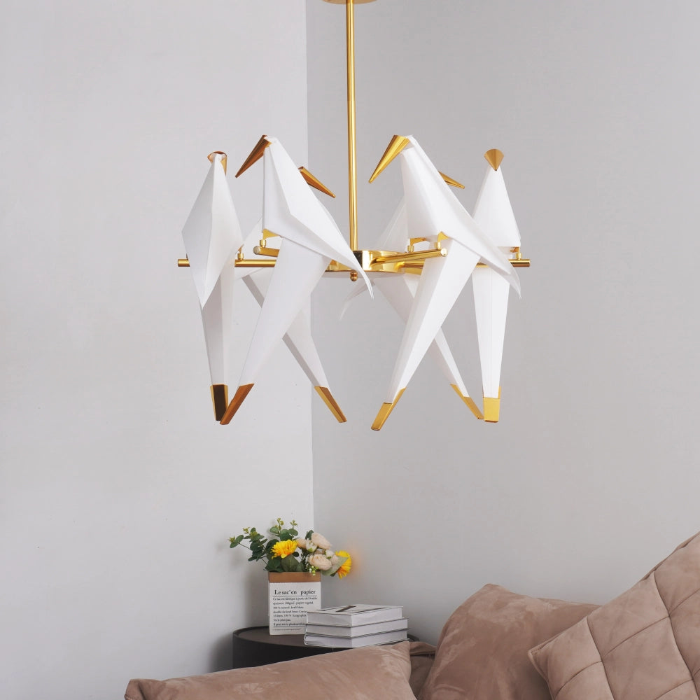Modern chandelier with white lampshades and gold accents in a living room setting.