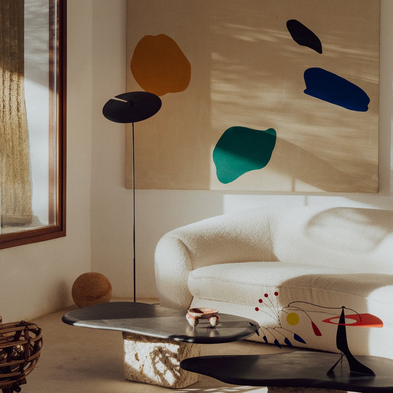 A floor lamp with a dark brown circular shade and slim metal stand, adding artistic charm to the space.