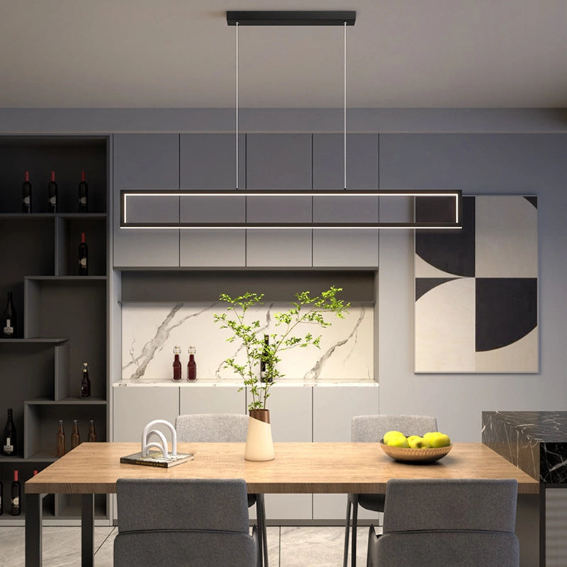 Modern rectangular pendant light hanging over a wooden dining table in a contemporary kitchen-dining space