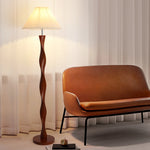 This is a spiral wooden column floor lamp. The dark brown solid wood lamp column is twisted in a twisted shape with flexible lines. With a white pleated lampshade, the warm light is soft. The simple design is suitable for a variety of styles, adding warmth and artistic feeling to the space.