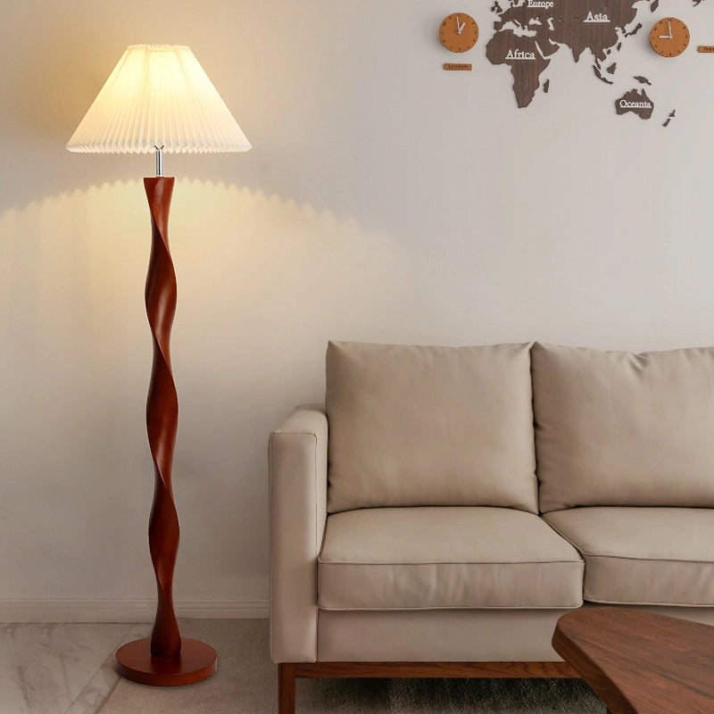This is a simple and warm living room scene. The main body is a spiral wooden column floor lamp, and the light beige sofa next to it has simple lines. The white wall above is hung with a wooden world map and clock decoration. The marble floor has a natural texture. The overall style is simple and comfortable, and the floor lamp becomes a unique artistic embellishment in the space.