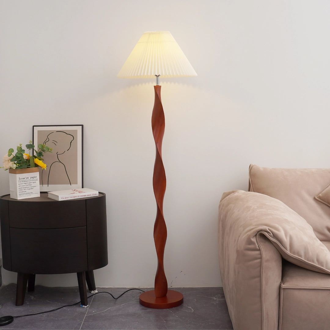 The dark brown walnut lamp post is in a twisted spiral shape. The solid wood texture rises and falls naturally with the arc. Each circle of spiral pattern is like a hand-carved annual ring. The interweaving of light and shadow reveals a warm texture. The white pleated lampshade on the top is like a blooming paper flower. The pleated texture is delicate and soft. When the warm light passes through, it casts a wavy halo on the wall. The metal base at the bottom of the lamp post
