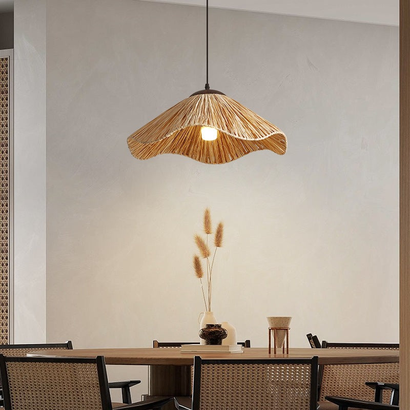 Handwoven straw pendant lamp casting warm geometric shadows over dining table