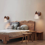Travertine Wabi-sabi Wall Lamps: Pair of wood-base lights with textured travertine shades, casting soft glow above a natural wood bedroom bed (wabi-sabi aesthetic).