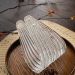 Closeup of ribbed textured butterfly glass shade for vintage semi flush ceiling light, clear rippled glass lamp component on wooden tray