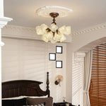 Vintage butterfly glass semi flush ceiling light installed in traditional bedroom, dark wood bed, french country interior, warm ambient lamp glow