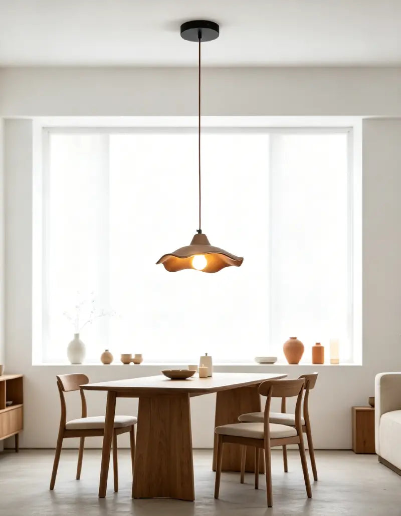 Wavy Cement Pendant Light hanging above a wooden dining table in a modern interior setting.